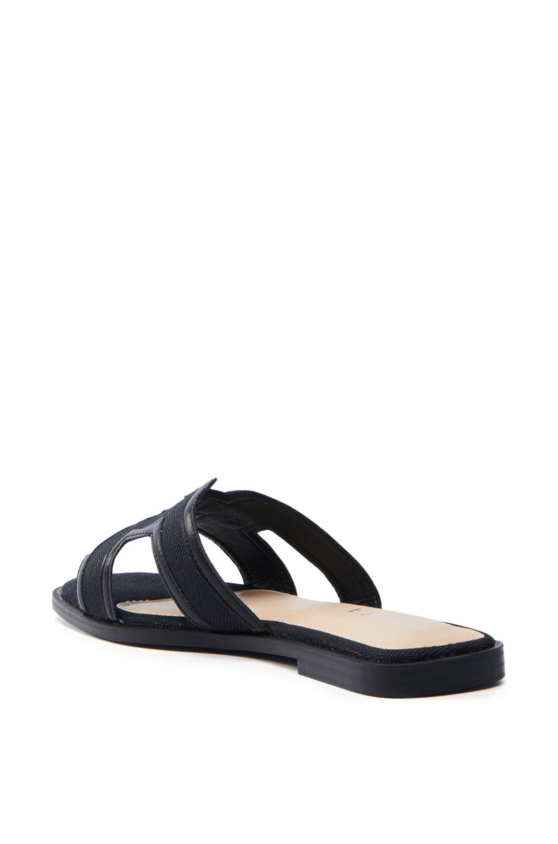 The AKIRA VITTORIA BLACK SANDAL showcases sleek faux leather with crisscross straps, a flat sole, and an open-toe design. Seen from the back and side against a white background, it combines style and simplicity for any casual look.