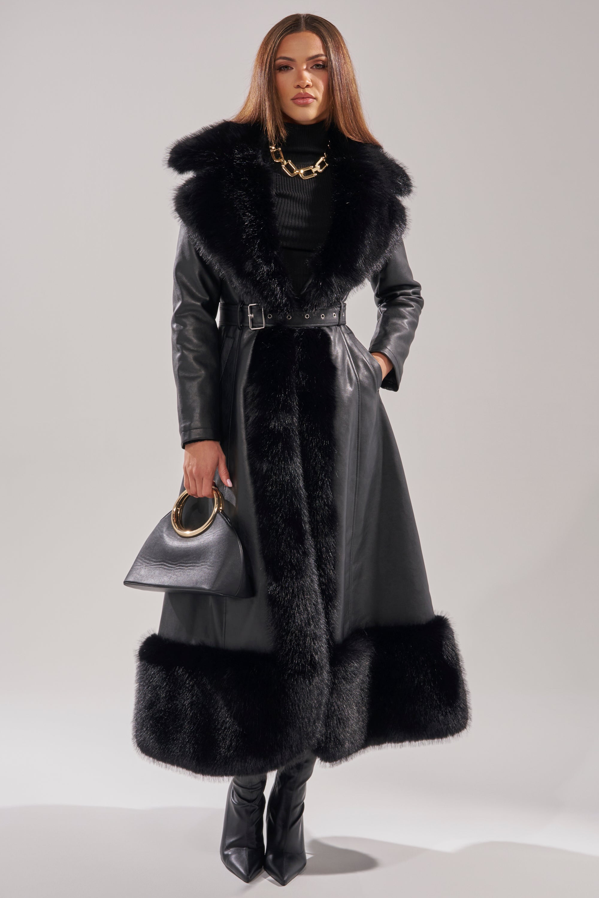 A woman in the VIVAN LONG PU TRENCH WITH FAUX FUR TRIM brings a stylish edge to her winter wardrobe.