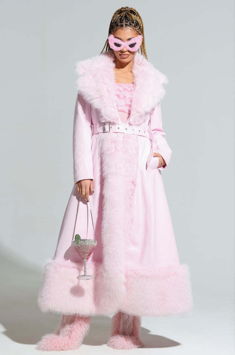 Dressed in the VIVIAN FUR TRIM COAT with its elegant pink fur trim and quilted satin lining, a person sports stylish cat-eye sunglasses. They're holding a large cocktail glass garnished with lime and wearing fluffy pink boots against a plain white backdrop.