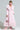 Dressed in the VIVIAN FUR TRIM COAT with its elegant pink fur trim and quilted satin lining, a person sports stylish cat-eye sunglasses. They're holding a large cocktail glass garnished with lime and wearing fluffy pink boots against a plain white backdrop.