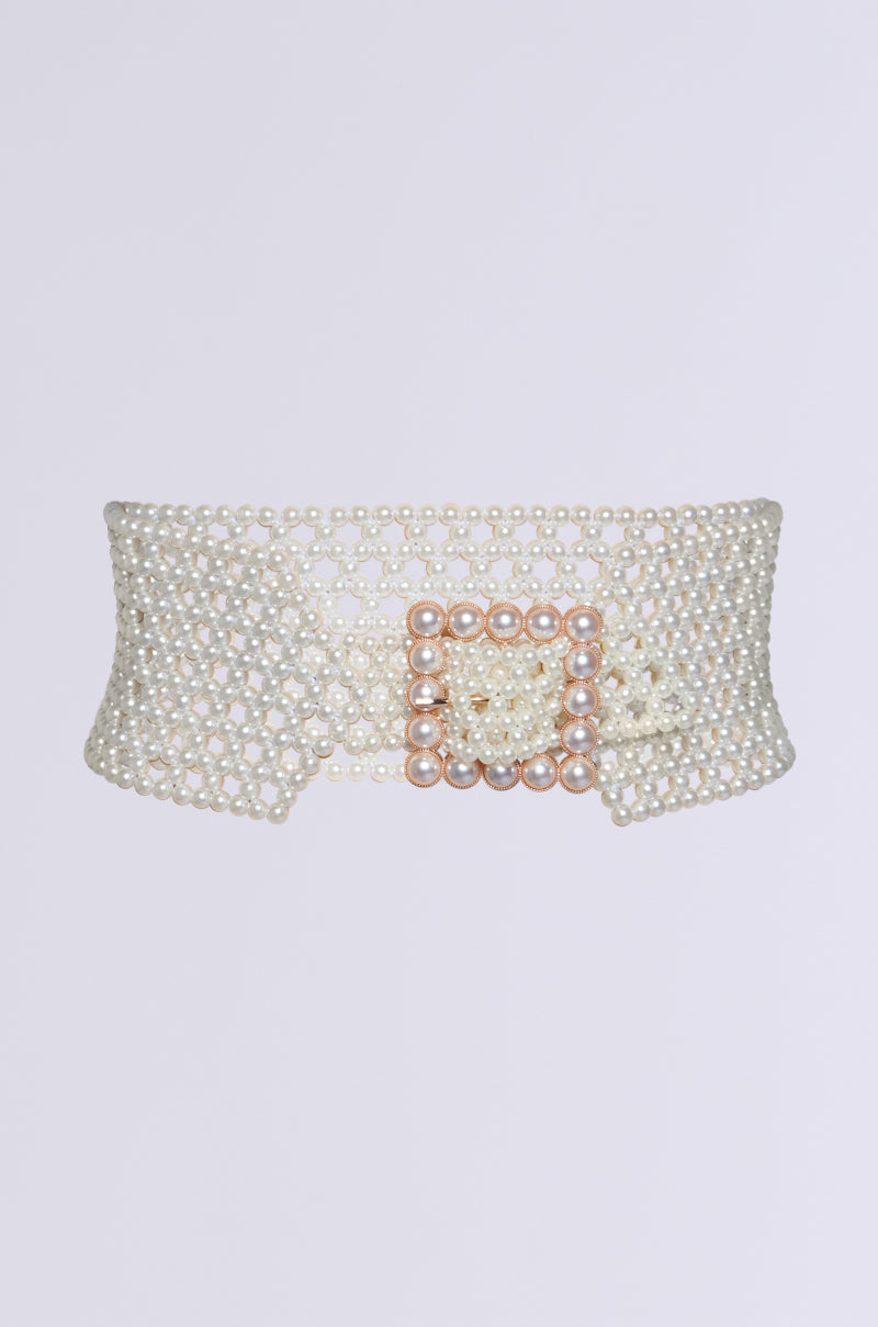 The PEARL PLEASE BELT is a wide belt made of interconnected pearl beads, featuring a square pearl buckle. It provides an adjustable fit for a waist-cinching effect against a plain white background. 0