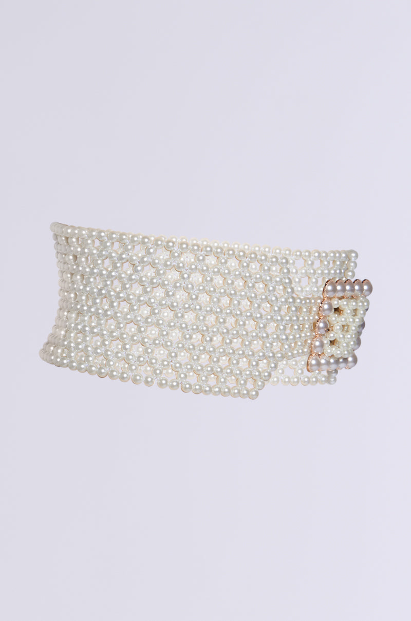 The PEARL PLEASE BELT, featuring a waist-cinching design made entirely of small pearl beads and a pearl-encrusted buckle, is showcased against a plain gray background.