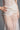 Wearing a sheer white lace dress with intricate patterns, the model showcases the STAY DRIPPIN PEARL BELT—an eye-catching faux pearl and bead statement piece draped at the waist. One hand rests on her hip; image is cropped at the torso.