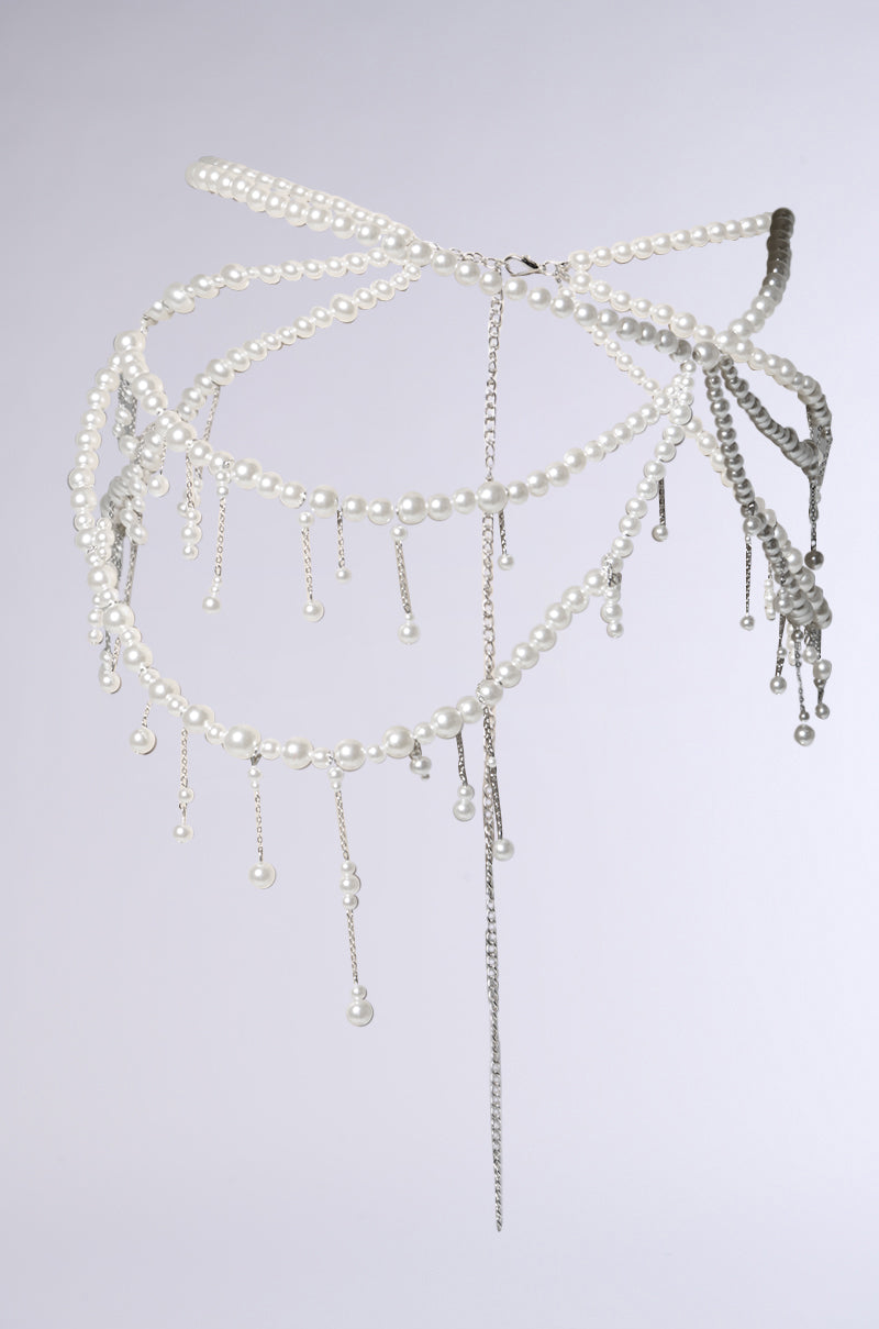 A sculptural headpiece of faux pearls, silver chains, and beads drapes in intricate loops with dangling accents, echoing the STAY DRIPPIN PEARL BELT, set against a plain light background.