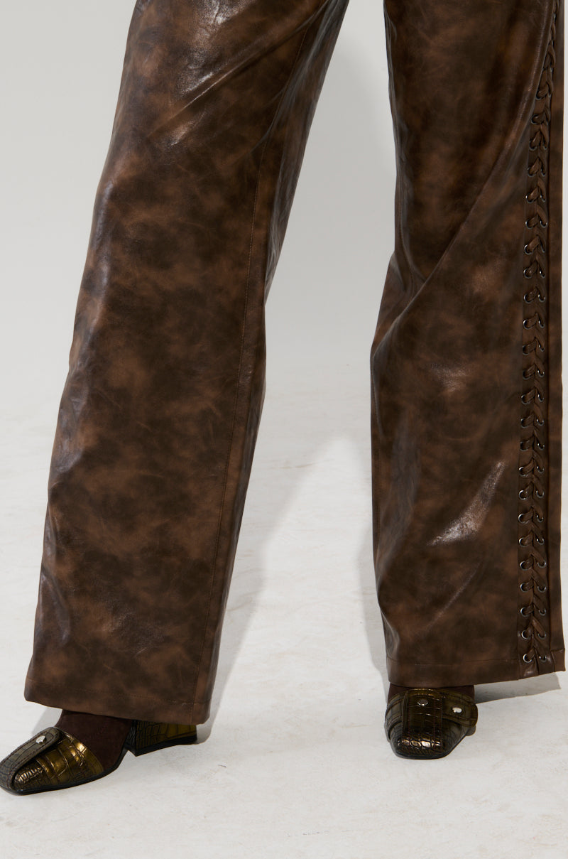 A person stands on a light surface, flaunting the AKIRA Label's UP TO IT LACE UP TROUSERS featuring elegant lace-up detailing on the side. Completing the chic look are dark brown textured shoes, ideal for any fashion-forward ensemble.