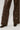 A person stands on a light surface, flaunting the AKIRA Label's UP TO IT LACE UP TROUSERS featuring elegant lace-up detailing on the side. Completing the chic look are dark brown textured shoes, ideal for any fashion-forward ensemble.