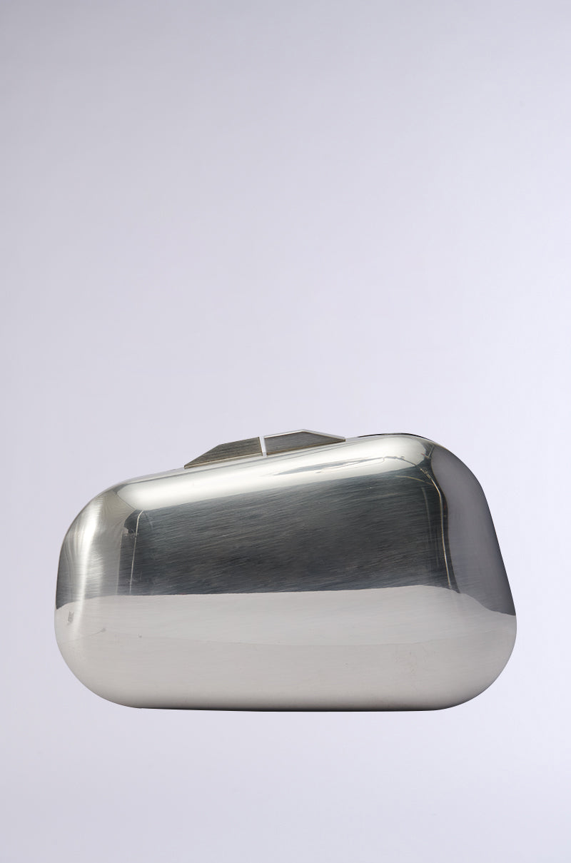 The METAL MANIA CLUTCH in a chic metallic silver showcases a simple rectangular shape with curved corners on a plain background. It offers a polished and smooth finish, complemented by a geometric clasp at the top, and comes with a detachable chain link strap for adaptable style. 0