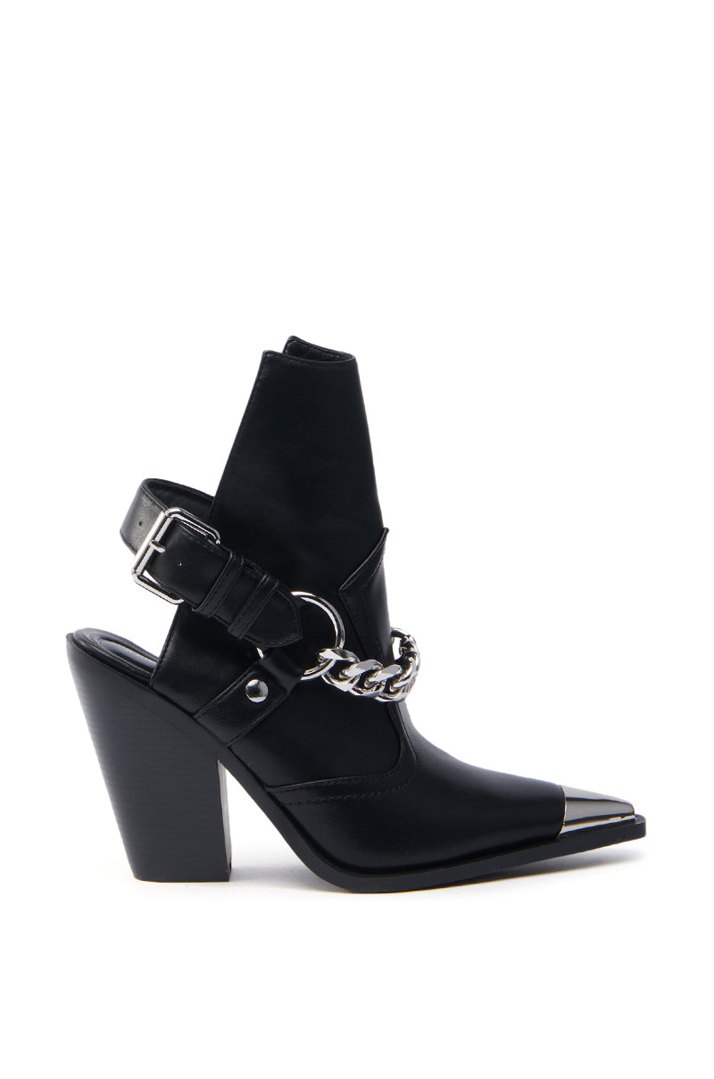 The AZALEA WANG WADE BLACK WESTERN BOOTIE is a black high-heeled ankle boot made from vegan leather, features a pointed silver metallic toe, cut-out sides, chunky heel, silver chain across the front, and a decorative buckle strap around the ankle, adding a Western flair.