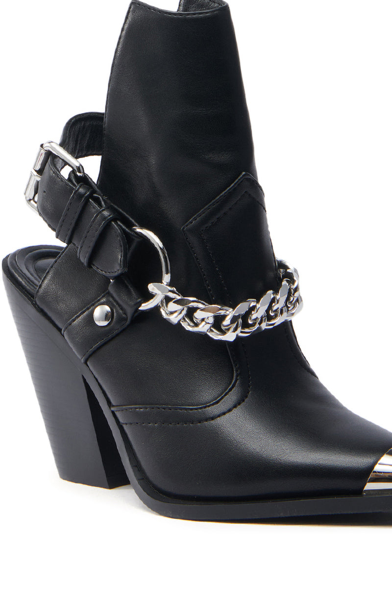 The AZALEA WANG WADE BLACK WESTERN BOOTIE is a black vegan leather, pointed-toe ankle boot with a chunky heel. It features a silver chain detail across the front, a metal buckle strap on the back, and a glossy finish that exudes a modern, edgy Western vibe.