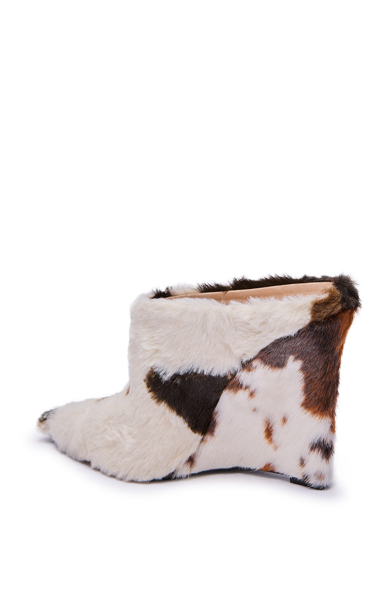 The AZALEA WANG WAFIYA MULTI WEDGE COW PATTERN FURRY PUMP is shown against a plain white background, featuring a pointed toe, hidden wedge heel, and white, brown, and black faux fur with a cowhide pattern.