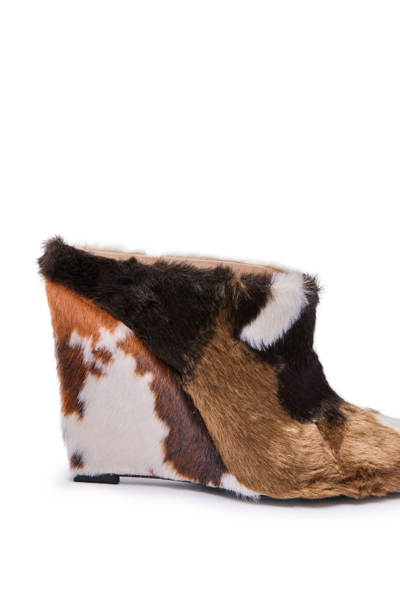 The AZALEA WANG WAFIYA MULTI WEDGE COW PATTERN FURRY PUMP features a unique wedge heel with multicolored faux fur in brown, black, white, and tan cow pattern. Photographed against a white background.