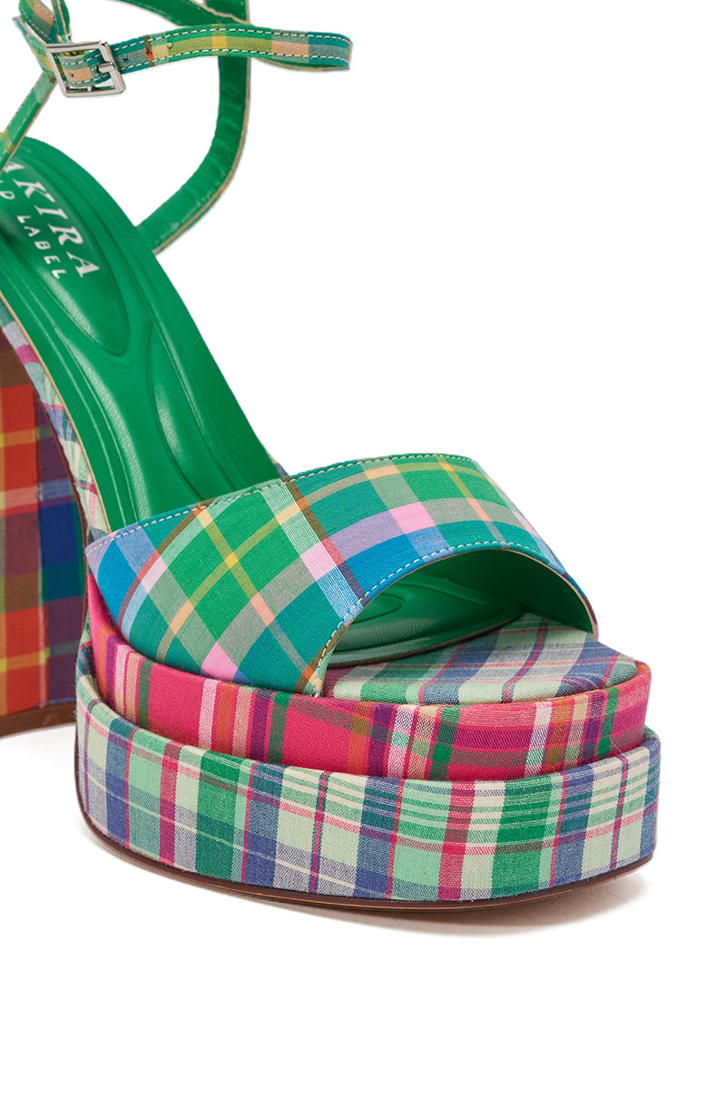 A close-up of the AKIRA GOLD WANDELLA GREEN PLAID PLATFORM SANDAL featuring a green insole and multicolor plaid fabric on the chunky heel, platform sole, and ankle strap. 6