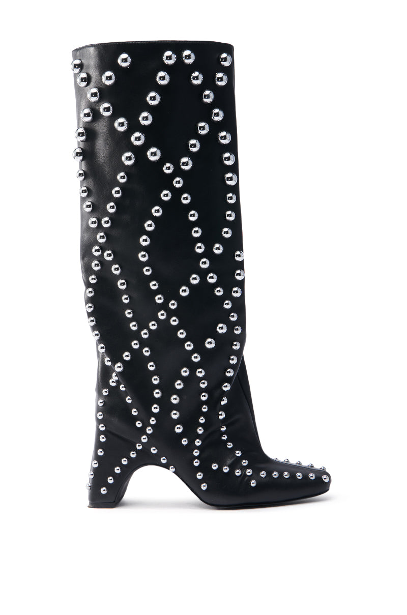 The AZALEA WANG WELLS BLACK EMBELLISHED BOOT is a knee-high boot made of vegan leather, featuring a curved chunky heel with silver studs in geometric diamond patterns, a slightly pointed toe, and a sleek glossy finish.