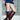 A person wearing a denim mini skirt, maroon top, and AZALEA WANG WELLS NEW BURGUNDY CROC BOOTS stands indoors in front of a glass block wall.