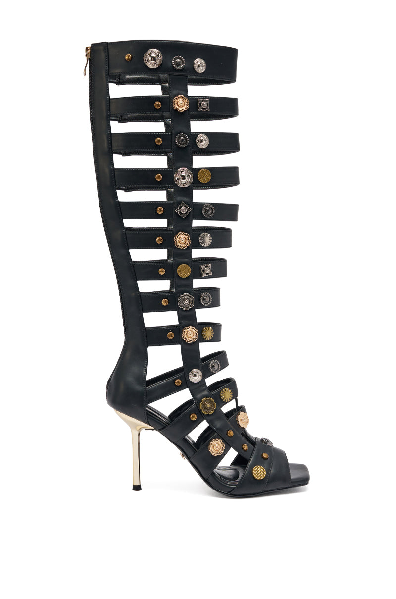 The AZALWA WANG Gold Wentworth Gladiator Sandal features knee-high, black straps with two-toned hardware and metallic studs, a stiletto heel, and open toe—an embellished style crafted to turn heads. 2
