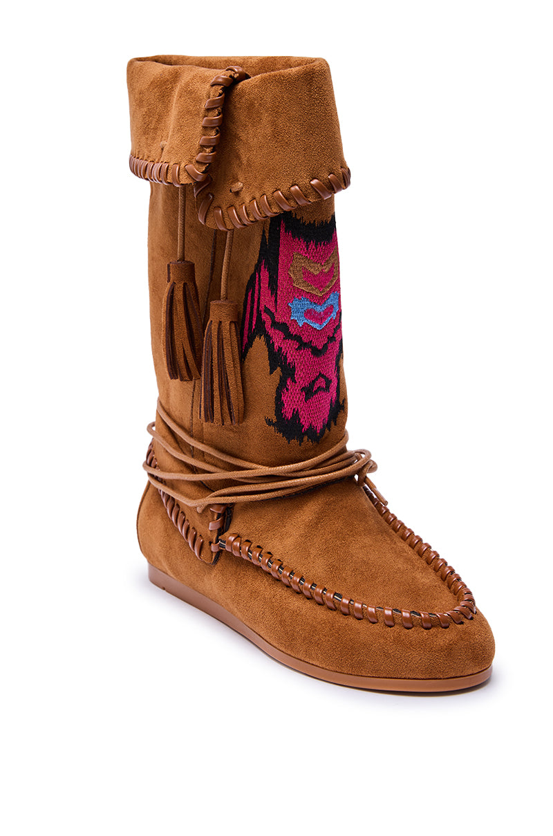 The AZALEA WANG WERET CHESTNUT FLAT BOOTIE features brown faux suede in a moccasin style with stitched details, a folded cuff, tassels, wraparound lace, and a vibrant pink and black geometric design on the front.