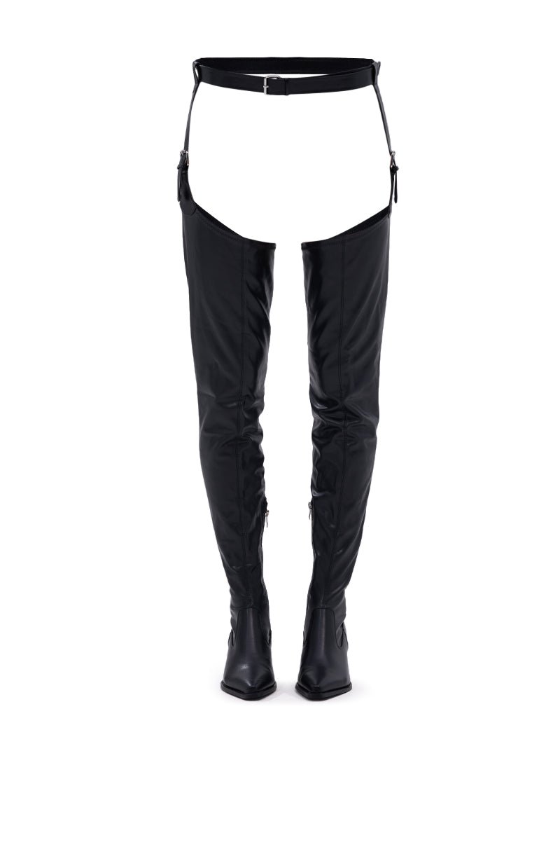 The AZALEA WANG WESTLANN BLACK PU CHAP BOOT features Western-inspired thigh-high black boots with a chap-style belt harness and open hip design, shown against a plain white background.