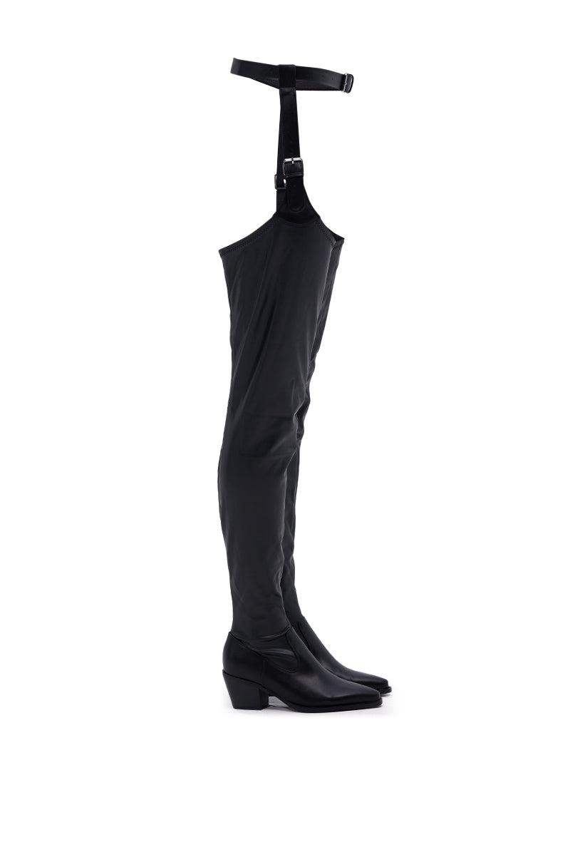 The AZALEA WANG WESTLANN BLACK PU CHAP BOOT is a stylish black thigh-high boot in faux leather, featuring a pointed toe, low block heel, and adjustable top strap with buckle for a secure fit.