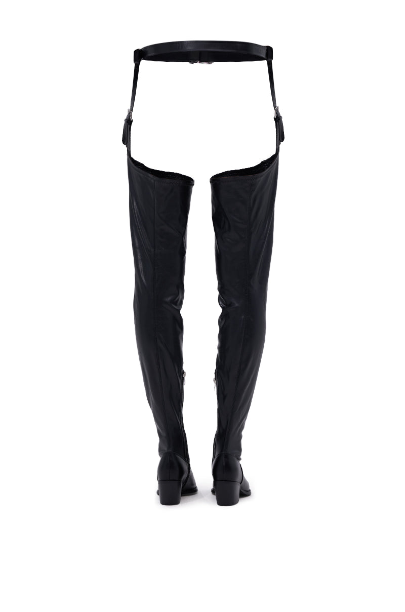 The AZALEA WANG WESTLANN BLACK PU CHAP BOOT is a pair of black, Western-inspired thigh-high boots with attached garter-style straps, shown upright against a white background.