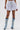 A person wears HEATHERED BUBBLE SHORT in light gray cotton with a high-rise fit, paired with knee-high light blue lace-up denim boots, standing against a plain white background.