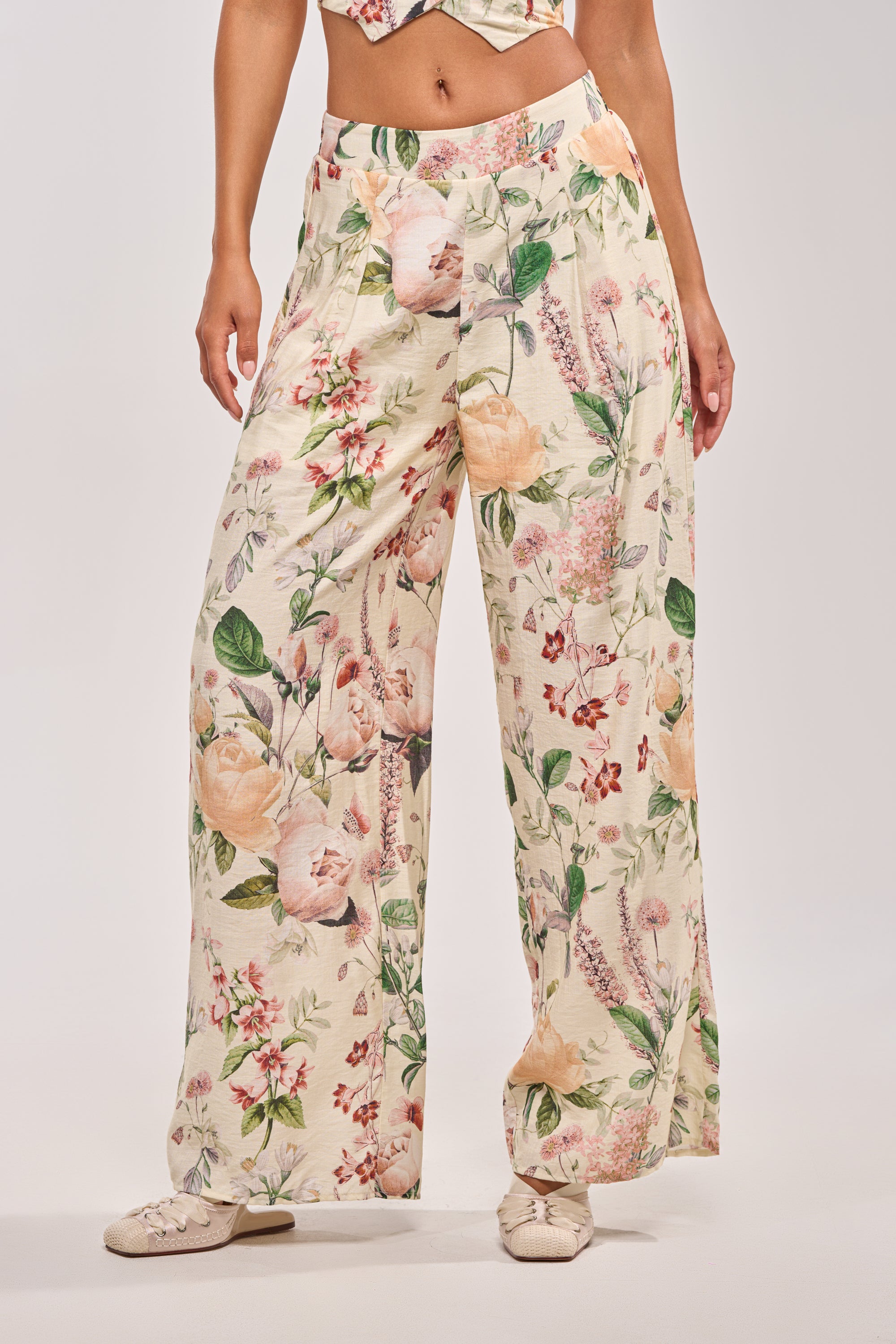 Wearing the LADY B TROUSER, featuring a loose, wide-leg silhouette and colorful floral print, a person stands against a plain light background with their head and upper chest out of frame.