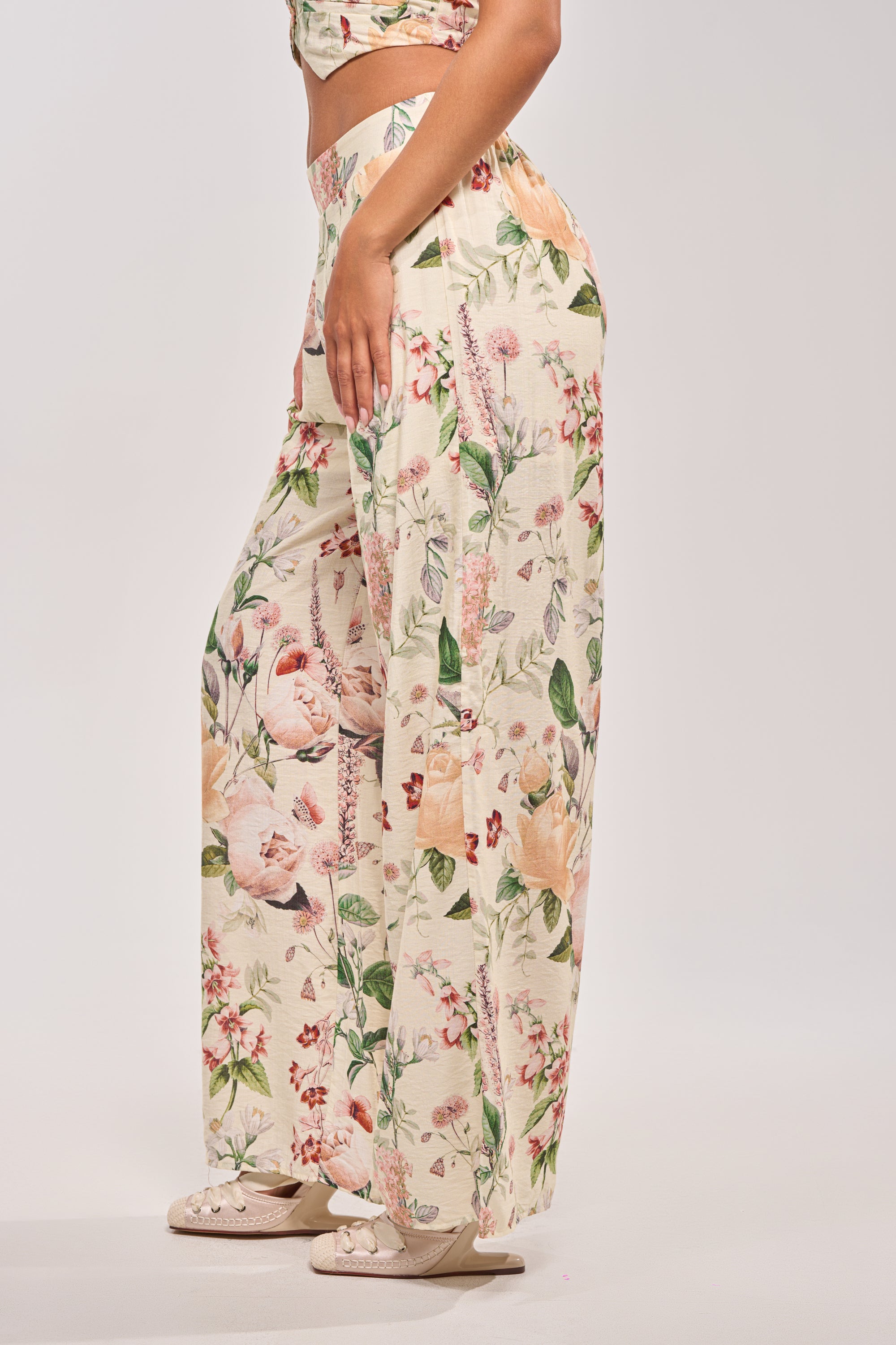 Wearing the LADY B TROUSER featuring a high-rise waist, wide-leg silhouette, and colorful floral print, paired with matching shoes against a plain light background.