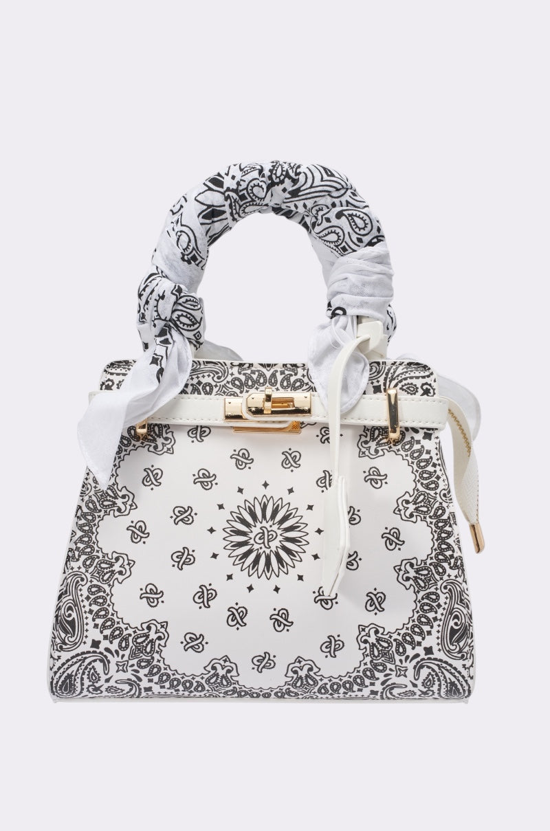 The VIVIENNE PAISLEY PRINT BAG features white paisley patterns with black floral bandana accents, gold hardware, and a matching fabric-wrapped handle—perfect as a chic western-inspired festival purse. 0