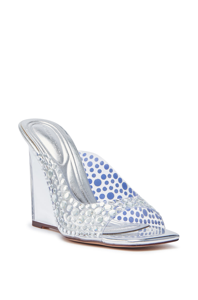 The AZALEA WANG WIDYA Silver Rhinestone Embellished PVC Wedge Sandal features a high heel, open toe, clear textured upper strap, shiny silver sole, transparent lucite wedge heel, and blue polka-dot insole.