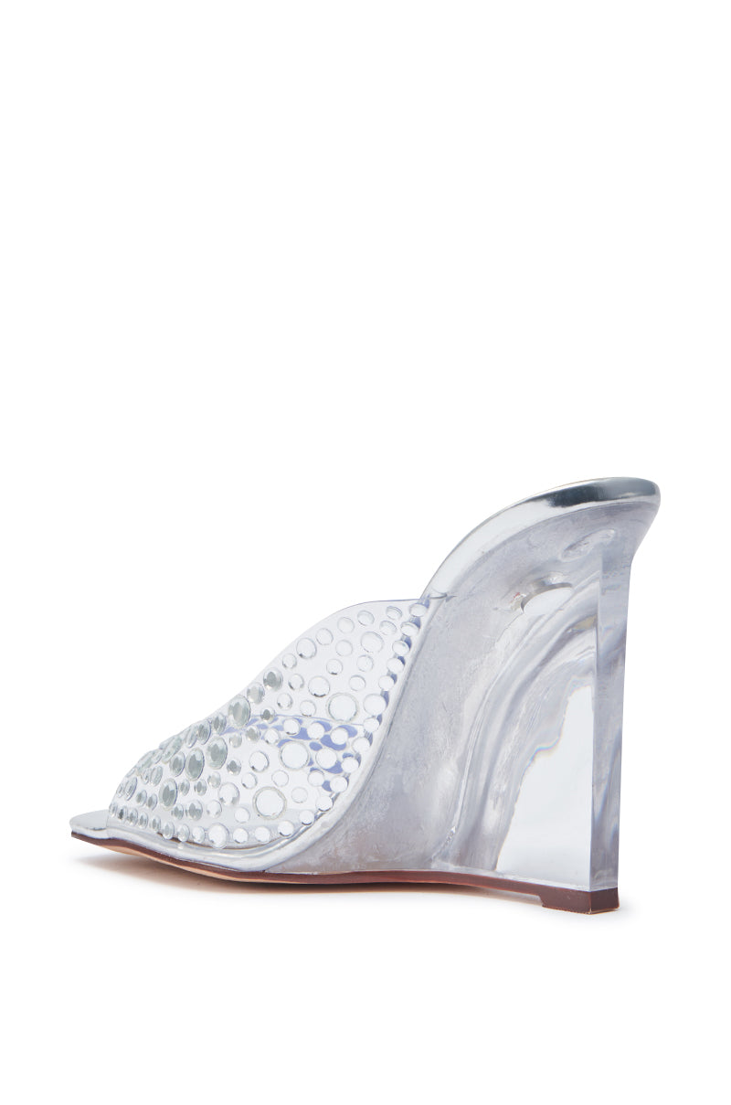 The AZALEA WANG WIDYA Silver Rhinestone Embellished PVC Wedge Sandal features a women's open-toe design with a clear, studded upper and marbled heel, shown from the side against a white background.