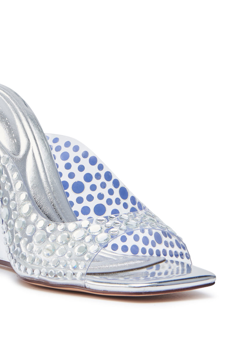 Close-up of the AZALEA WANG WIDYA Silver Rhinestone Embellished PVC Wedge Sandal with a textured, reflective open toe, clear circular rhinestones, against a white background with blue polka dots visible through the side.