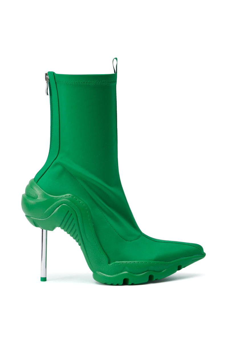 The AZALEA WANG WILBER BOOTIE WITH STRETCH NEOPRENE IN GREEN is a striking high-heeled boot featuring a distinctive design with a wavy sole and metallic stiletto heel. This pointy toe bootie presents a futuristic appearance, complete with a fitted ankle and side zipper. 2