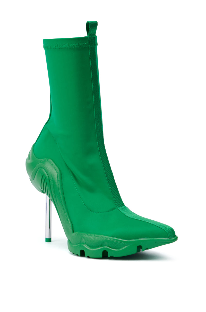 The AZALEA WANG WILBER BOOTIE WITH STRETCH NEOPRENE IN GREEN is a fashion-forward boot showcasing a unique design with a pointy toe and metallic stiletto heel in shiny silver. This stylish bootie extends above the ankle, offering a sleek and modern aesthetic, while its stretch neoprene construction ensures added comfort and style. 3
