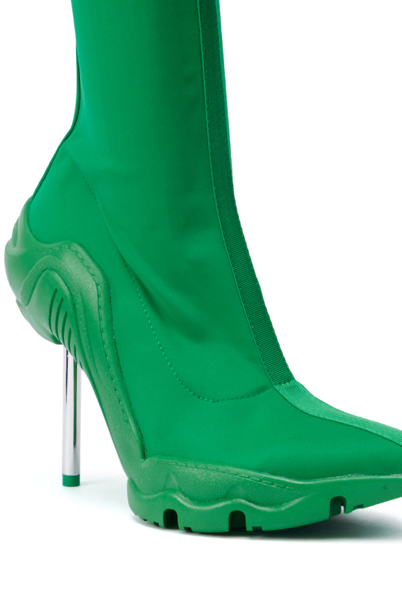 Introducing the AZALEA WANG WILBER BOOTIE WITH STRETCH NEOPRENE IN GREEN: This vibrant green bootie features a pointy toe, unique textured rubber sole, and sleek metallic stiletto heel. The side showcases a smooth fabric finish enhanced by stretch neoprene, creating a modern and futuristic design. 5