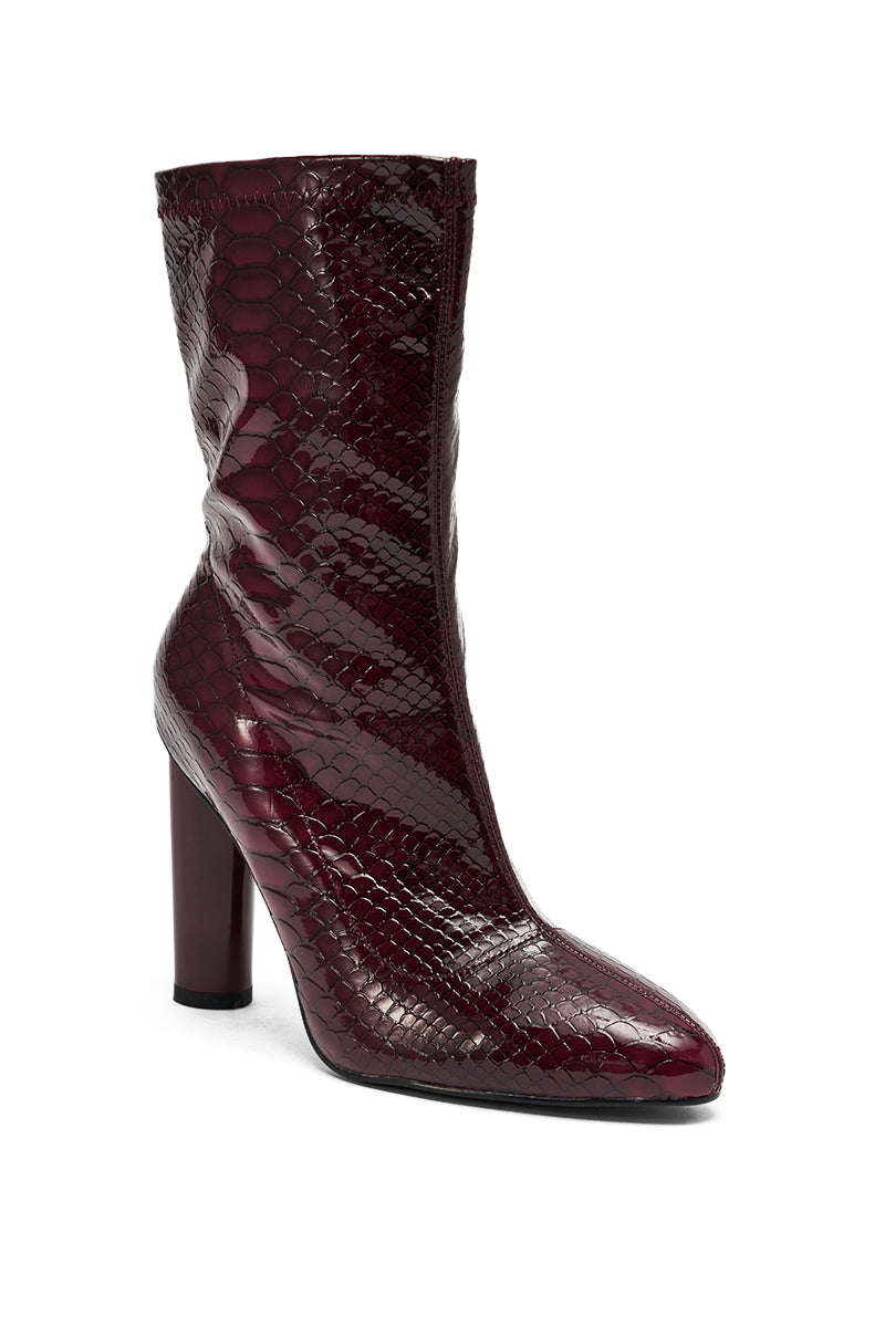The AZALEA WANG WINGROVE BURGUNDY CHUNKY HEEL CROCODILE BOOTIE is a glossy, mid-calf bootie with a high chunky heel, pointed toe, and faux crocodile textured pattern in rich burgundy.