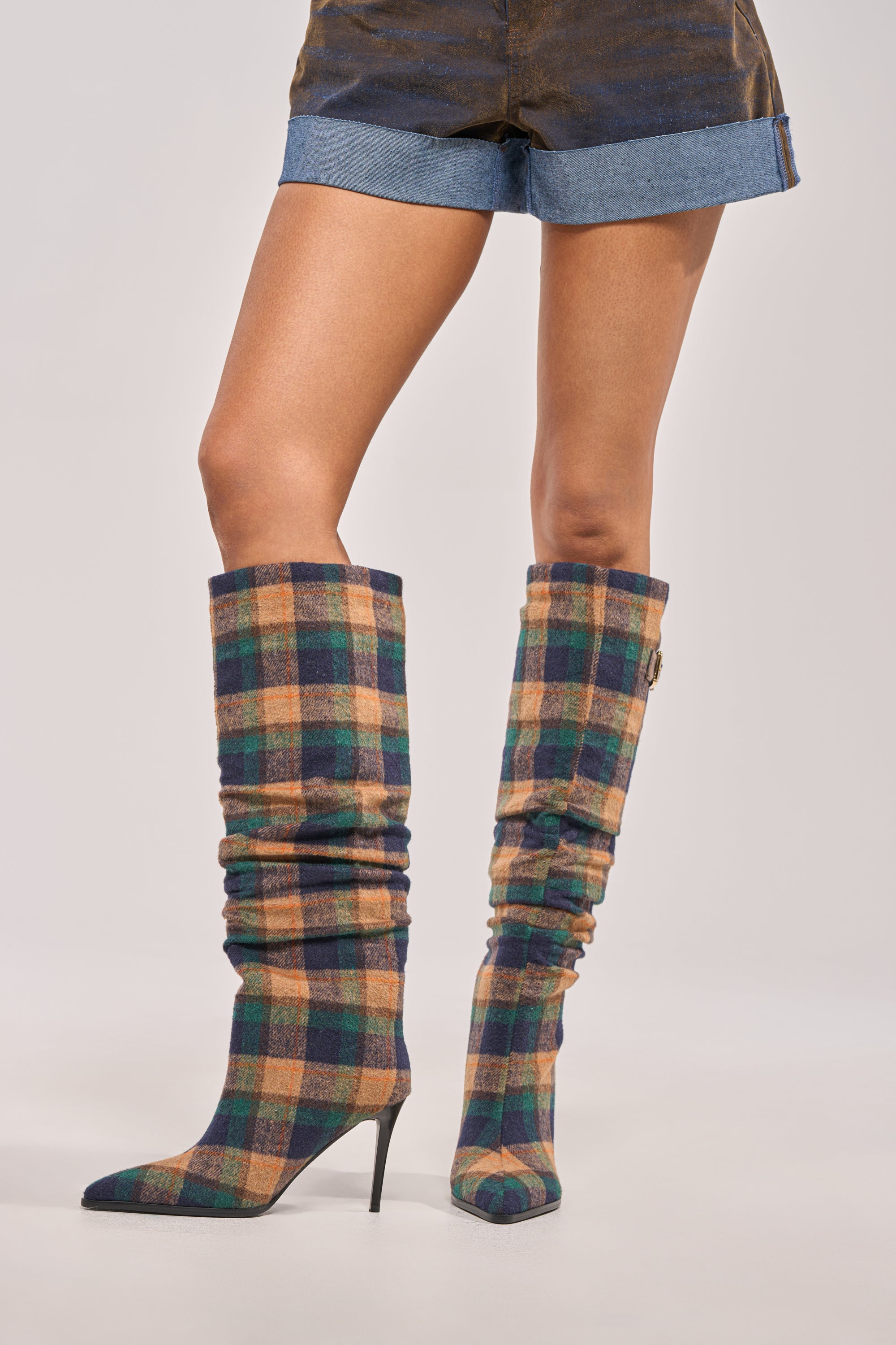 A person wearing the AZALEA WANG WISHBONE PLAID PRINT STILETTO BOOT and denim shorts stands against a plain background.
