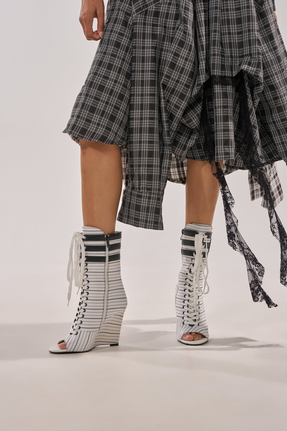 A person stands against a plain light background wearing a black-and-white plaid skirt and AZALEA WANG WYATT WHITE STRIPED NAUTICAL OPEN TOE BOOTIE. 2