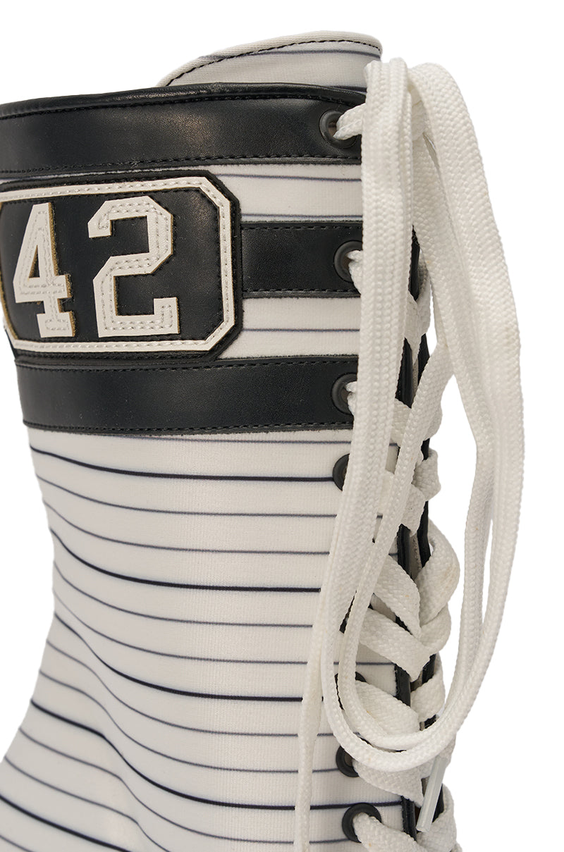 A close-up of the AZALEA WANG WYATT WHITE STRIPED NAUTICAL OPEN TOE BOOTIE, a white lace-up mid-calf bootie with black horizontal stripes and a black and white “42” patch near the top. 6