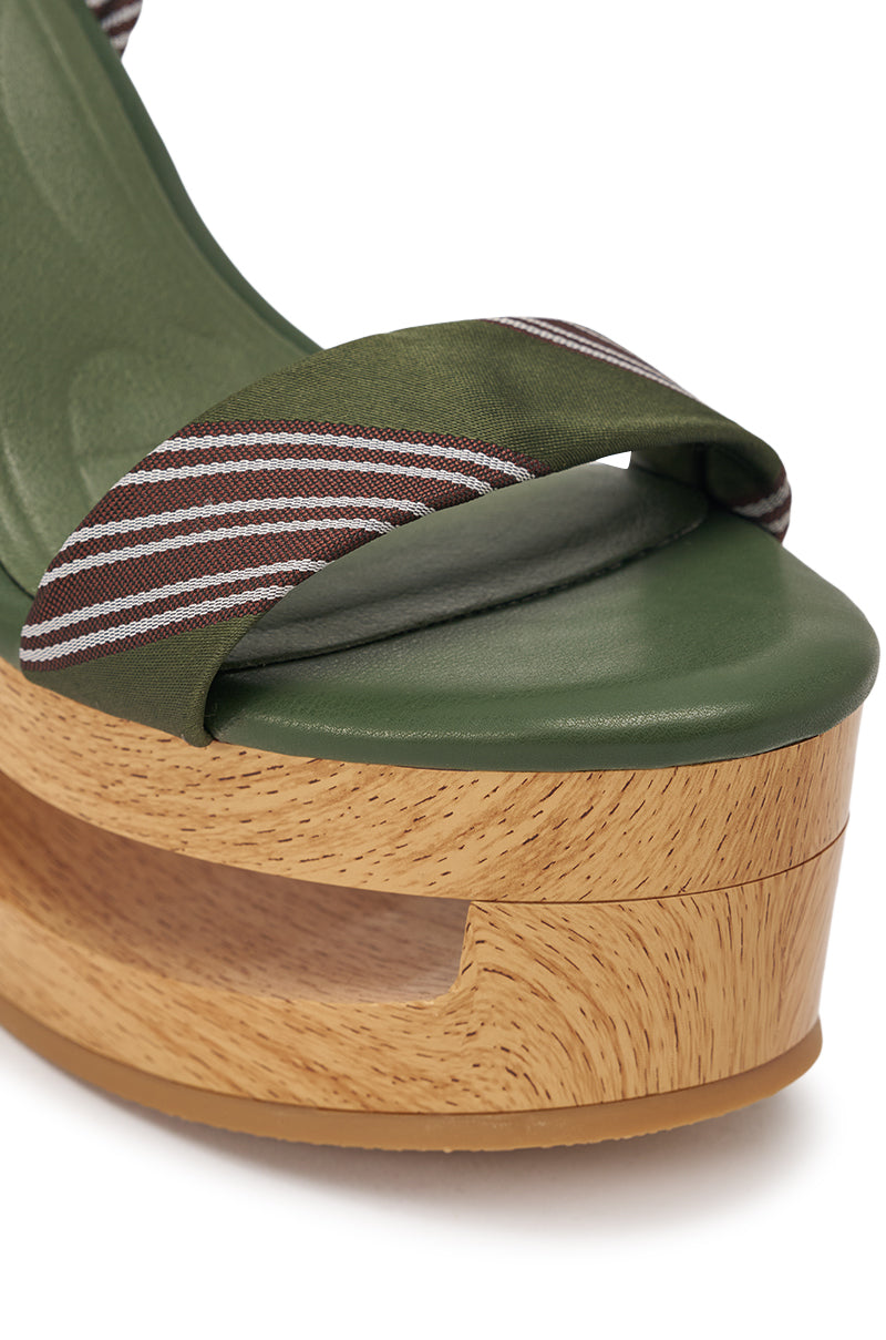 A close-up of the AKIRA GOLD WYNN GREEN TIE LACE UP NOVELTY WEDGE SANDAL, featuring a green footbed, green-brown-white striped fabric strap, and wooden platform sole with cut-out detail. 6
