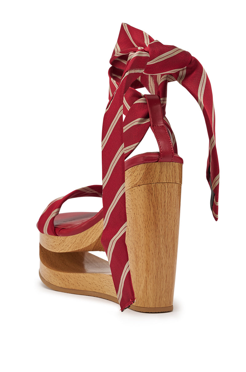 The AZALEA WANG WYNN RED TIE LACE UP WEDGE is a striped sandal with a wooden platform heel and red and white fabric straps that wrap around the ankle in a bow, shown from the back at an angle. 5