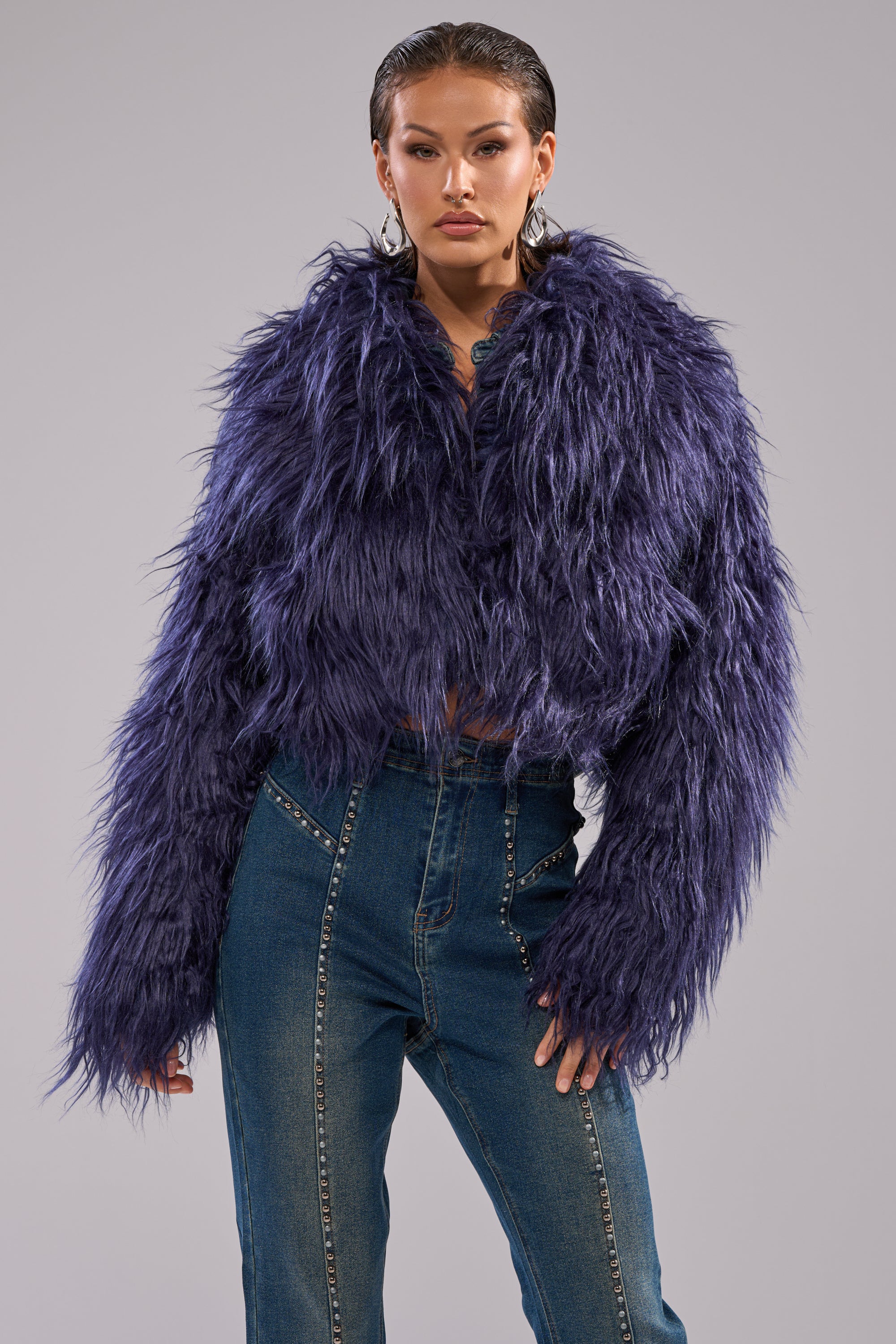 A person wears the LIFE OF THE PARTY FAUX FUR cropped navy coat with high-waisted blue jeans, standing confidently against a plain gray background.
