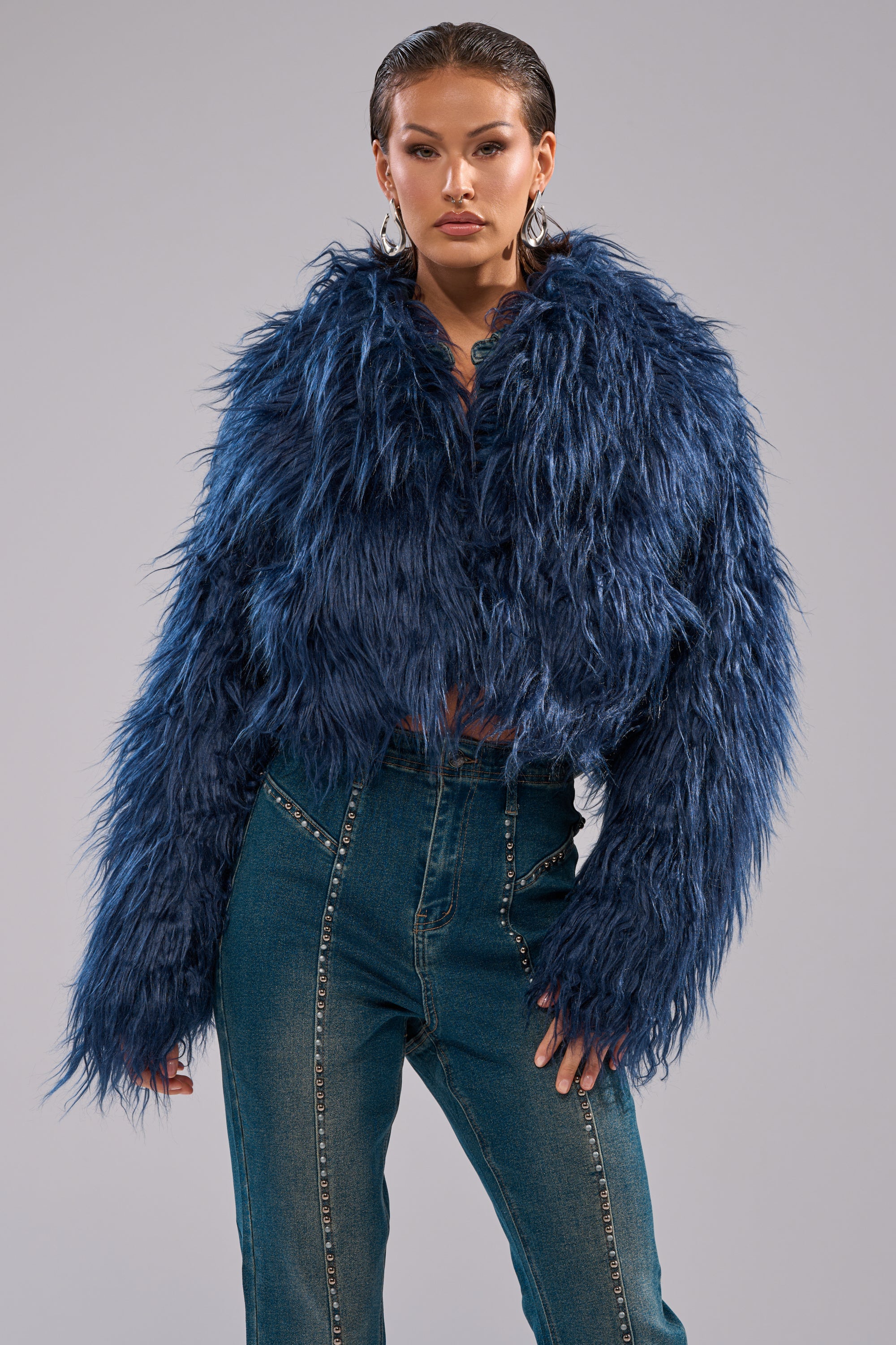 A woman wears the LIFE OF THE PARTY FAUX FUR, a modern, navy blue cropped jacket that exudes elegance. 4