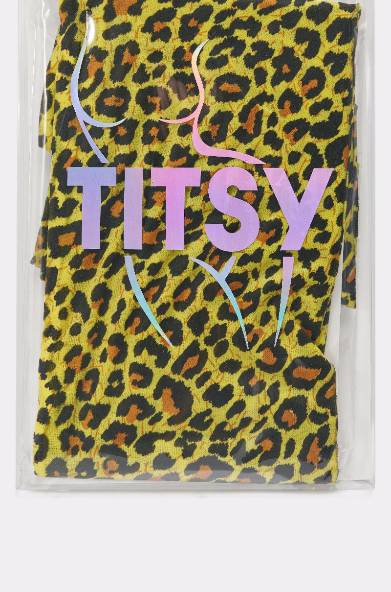 A package of CHEETAH GURL TIGHTS featuring yellow, black, and brown leopard-print festival tights, with "TITSY" branding and pink and purple stylized outlines of a woman's body printed on the clear packaging—ideal for bold looks. 6