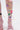 Close-up of legs in ITS POPPIN EMBELLISHED TIGHTS—white fishnet with floral and sequin details—paired with pink strappy high-heeled sandals, set against a plain white background.