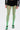 Someone stands against a plain white background wearing GREEN WITH NO ENVY TIGHTS—vibrant green fishnet tights made from stretchy material—paired with a black ruffled mini skirt, a black and white jacket, and zippered open-toe sandals.