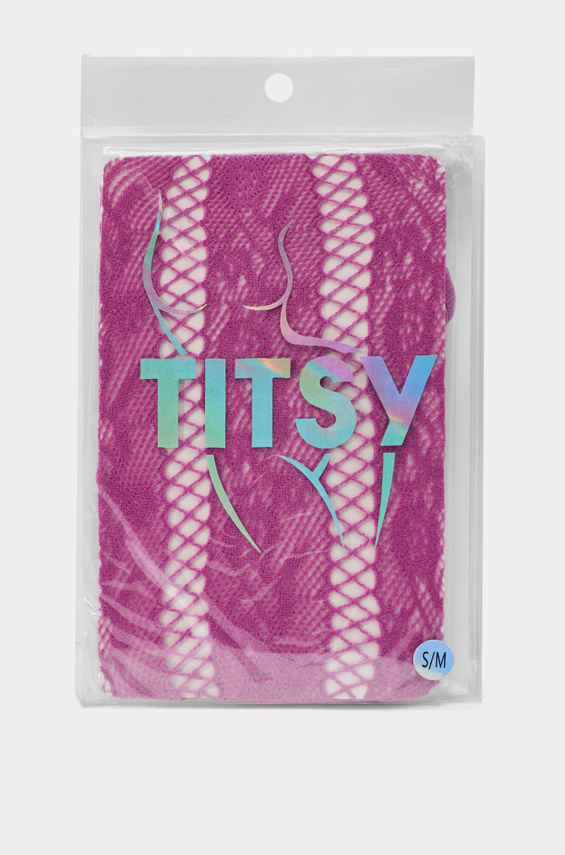 FEMME TIGHTS IN PINK—a pink lace lingerie piece with fishnet panels, recalling pink fishnet tights—comes in a clear bag labeled “TITSY” in iridescent letters, with a size S/M tag at the bottom right. 2