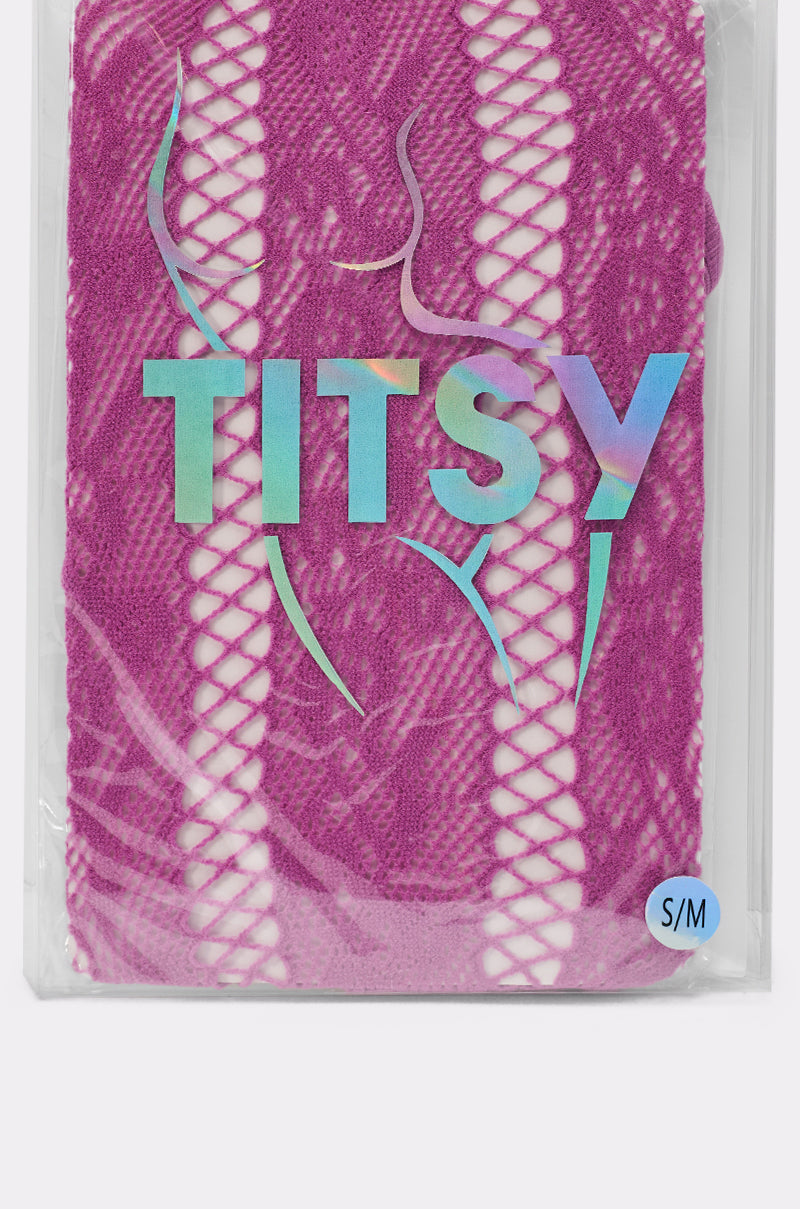 A package of FEMME TIGHTS IN PINK with a violet pattern. The label reads "TITSY" in iridescent letters, displays a simple outline of a woman's torso, and has an "S/M" size sticker in the bottom right corner. 3