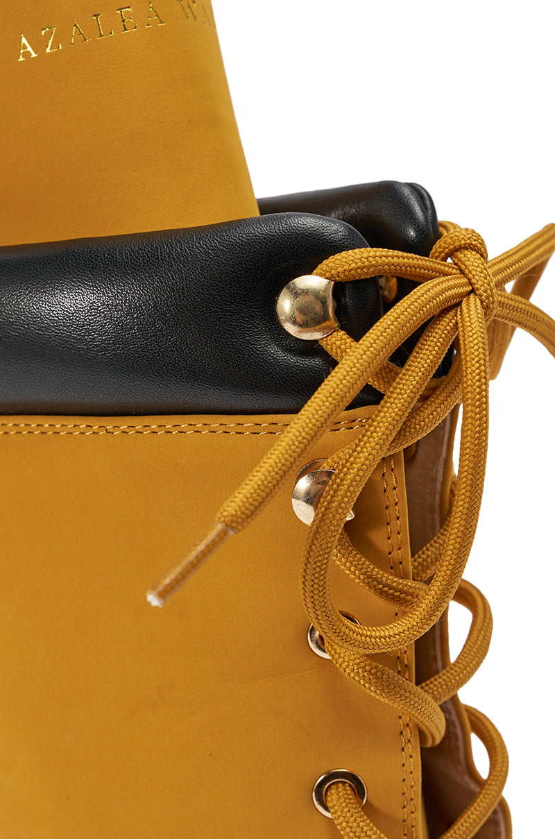 Close-up of the AZALEA WANG XIOMARAN YELLOW BOOTIE in faux suede with yellow laces, gold eyelets, black padded collar, and "AZALEA" partially visible in gold on the inner lining.