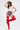 A woman poses confidently in a white tank top with red stars, denim shorts, a cowboy hat, and AZALEA WANG XOMARIA RED FAUX SUEDE WESTERN CHAP BOOTS against a plain, light background.