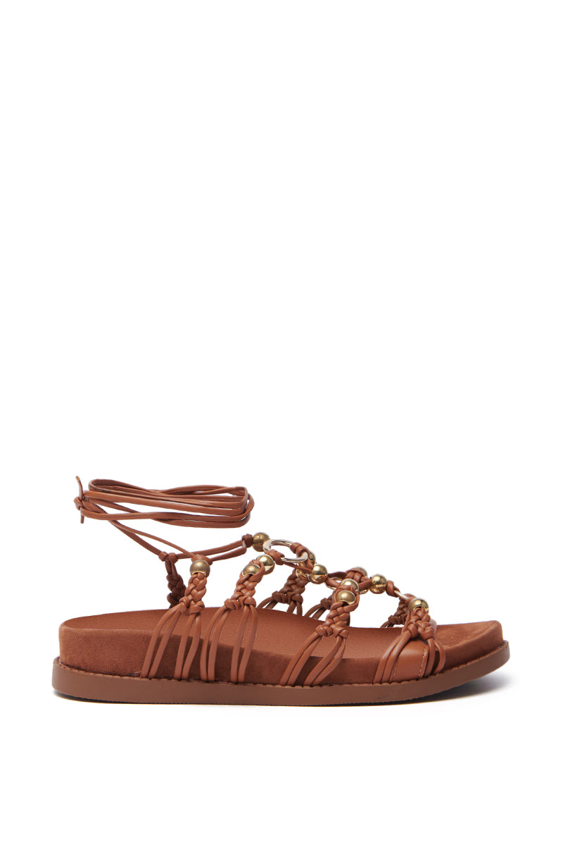 AZALEA WANG XYLA brown faux suede sandal features braided straps, metallic gold bead accents, lace-up ankle design, and cushioned sole.