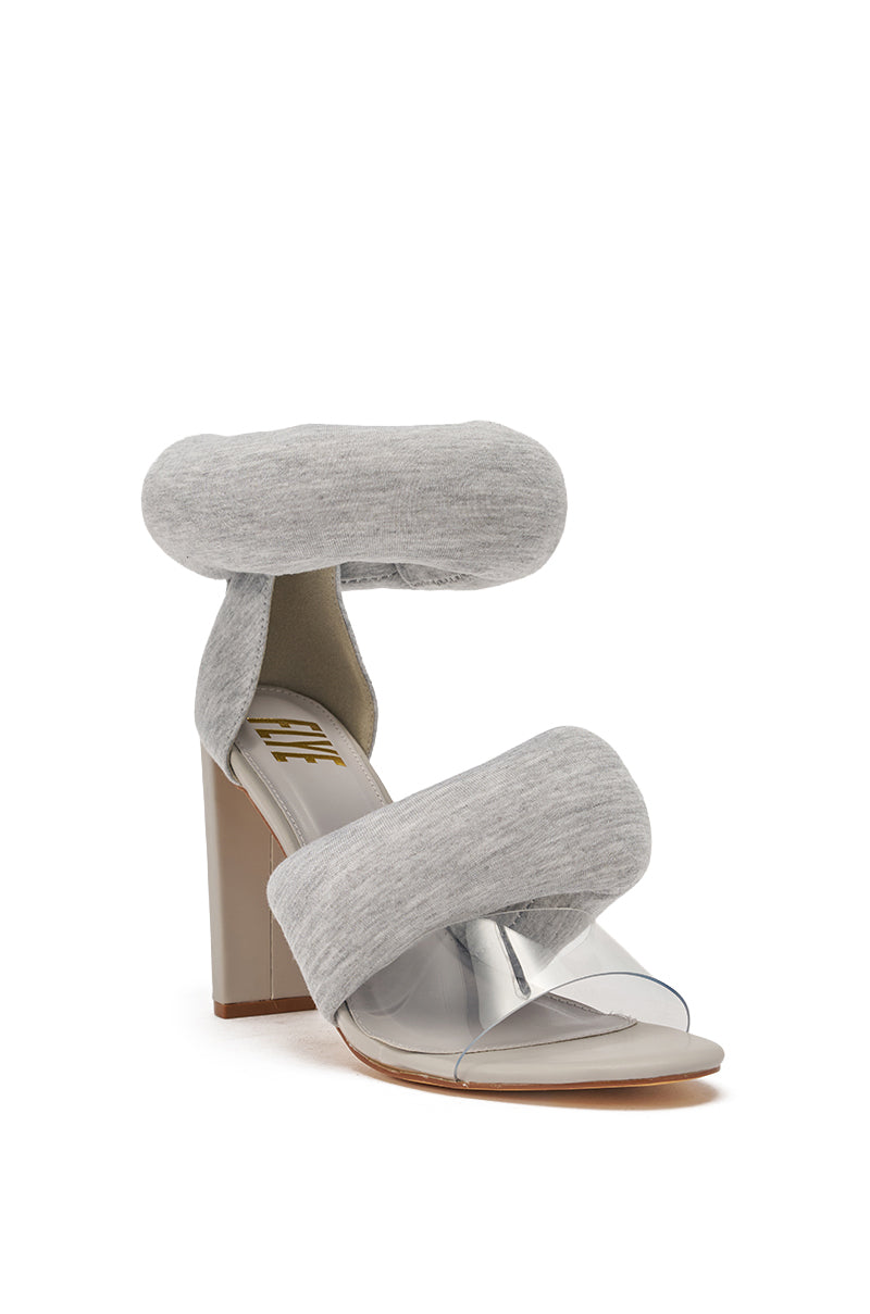 The YANIX GREY PUFF SLIP ON SANDAL features chunky heels, pale grey jersey knit straps over the toes and ankle, a clear plastic band across the foot, and a cushioned beige insole with gold branding. 4